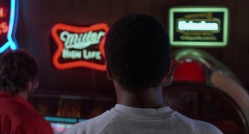 Movie still from “Blood Simple” (1984), directed by Joel Coen – A man standing in front of a neon sign; Close Up shot, Low angle