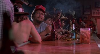 Movie still from “Blood Simple” (1984), directed by Joel Coen – A group of people sitting at a table drinking beer; Medium shot, Over the shoulder angle
