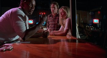 Movie still from “Blood Simple” (1984), directed by Joel Coen – A group of people sitting at a table in a bar; Medium shot, Over the shoulder angle