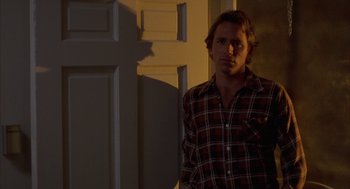 Movie still from “Blood Simple” (1984), directed by Joel Coen – A man standing in front of a white door; Medium shot, Over the shoulder angle