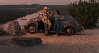 Movie still from “Blood Simple” (1984), directed by Joel Coen – A man and a woman standing next to an old car; Wide shot, High angle