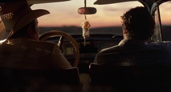 Movie still from “Blood Simple” (1984), directed by Joel Coen – A man riding in the back of a car; Medium shot, Low angle