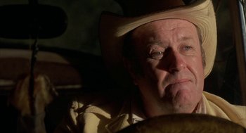 Movie still from “Blood Simple” (1984), directed by Joel Coen – An older man wearing a cowboy hat looking at the camera; Close Up shot, Over the shoulder angle