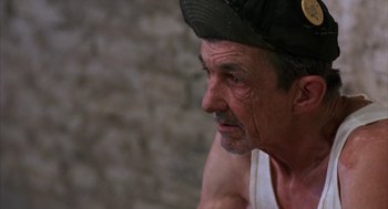 Movie still from “Blood Simple” (1984), directed by Joel Coen – An older man wearing a hat looking to his left; Close Up shot, Low angle