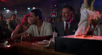 Movie still from “Blood Simple” (1984), directed by Joel Coen – A group of people sitting at a bar; Medium shot, Low angle