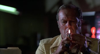 Movie still from “Blood Simple” (1984), directed by Joel Coen – An older man lighting a cigarette with a cigarette holder; Close Up shot, Low angle
