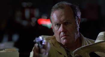 Movie still from “Blood Simple” (1984), directed by Joel Coen – A man holding a gun in his right hand; Close Up shot, Low angle