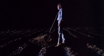 Movie still from “Blood Simple” (1984), directed by Joel Coen – A man standing in the middle of a field with a shovel; Wide shot, High angle
