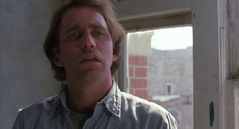 Movie still from “Blood Simple” (1984), directed by Joel Coen – A person wearing a blue shirt near a window; Close Up shot, Low angle
