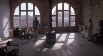 Movie still from “Blood Simple” (1984), directed by Joel Coen – A person standing in a room with a television set; Wide shot, High angle