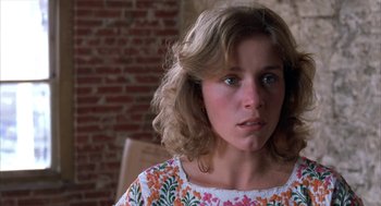 Movie still from “Blood Simple” (1984), directed by Joel Coen – A young woman with long blonde curly hair wearing a floral print shirt; Close Up shot, Over the shoulder angle