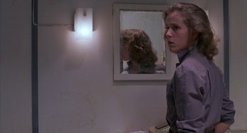 Movie still from “Blood Simple” (1984), directed by Joel Coen – A woman standing in front of a bathroom mirror; Medium shot, Low angle