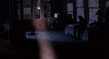 Movie still from “Blood Simple” (1984), directed by Joel Coen – A person sitting on a chair in a dark room; Extreme Wide shot, High angle