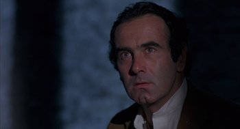 Movie still from “Blood Simple” (1984), directed by Joel Coen – A person wearing a suit and tie; Close Up shot, Low angle