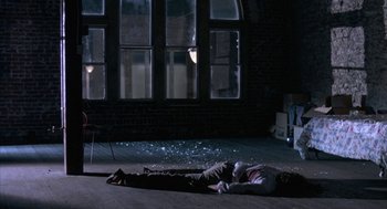 Movie still from “Blood Simple” (1984), directed by Joel Coen – A person laying on the ground in a dark room; Wide shot, High angle