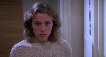Movie still from “Blood Simple” (1984), directed by Joel Coen – A young woman in a white sweater looking at the camera; Close Up shot, Low angle