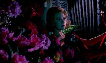 Movie still from “Blood and Black Lace” (1964), directed by Mario Bava – A woman with a bird on her shoulder in front of a bunch of flowers; Medium shot, Low angle