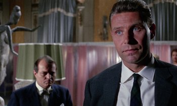 Movie still from “Blood and Black Lace” (1964), directed by Mario Bava – A man in a suit and tie standing next to another man in a suit and tie; Close Up shot, Low angle