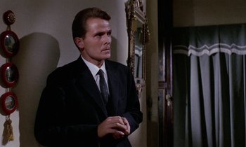 Movie still from “Blood and Black Lace” (1964), directed by Mario Bava – A man wearing a suit and tie standing in front of a mirror; Medium shot, Low angle