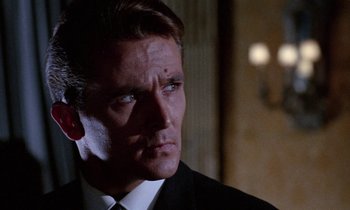 Movie still from “Blood and Black Lace” (1964), directed by Mario Bava – A man in a black suit and white tie; Close Up shot, Low angle