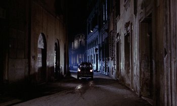 Movie still from “Blood and Black Lace” (1964), directed by Mario Bava – A car driving down a street at night; Extreme Wide shot, High angle