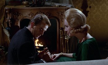 Movie still from “Blood and Black Lace” (1964), directed by Mario Bava – A man and a woman sitting in front of a fire place; Medium shot, Over the shoulder angle