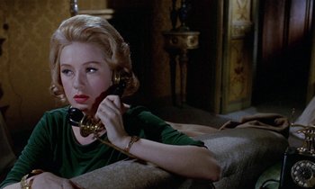 Movie still from “Blood and Black Lace” (1964), directed by Mario Bava – A woman sitting on a couch talking on a phone; Close Up shot, High angle