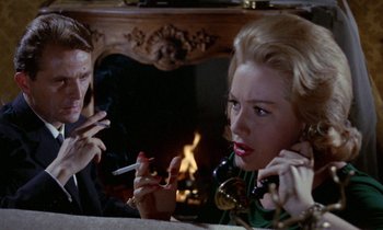 Movie still from “Blood and Black Lace” (1964), directed by Mario Bava – A man and a woman sitting in front of a fireplace; Close Up shot, High angle
