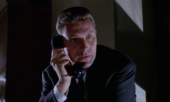 Movie still from “Blood and Black Lace” (1964), directed by Mario Bava – A man in a suit and tie holding a cell phone to his ear; Close Up shot, Low angle