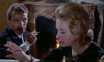 Movie still from “Blood and Black Lace” (1964), directed by Mario Bava – A man and a woman sitting in front of a fireplace; Close Up shot, Over the shoulder angle