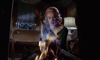 Movie still from “Blood and Black Lace” (1964), directed by Mario Bava – A woman sitting in front of a fire in a living room; Medium shot, Over the shoulder angle