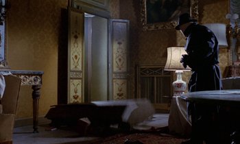 Movie still from “Blood and Black Lace” (1964), directed by Mario Bava – A living room with an open door and a lamp on the floor; Wide shot, Low angle