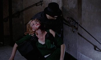 Movie still from “Blood and Black Lace” (1964), directed by Mario Bava – A man and a woman in green dress and black hat; Medium shot, Overhead angle