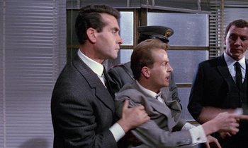 Movie still from “Blood and Black Lace” (1964), directed by Mario Bava – Two men in suits and ties one of them is holding a man in a suit; Medium shot, Over the shoulder angle
