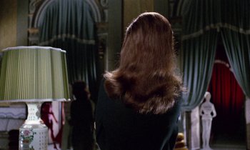 Movie still from “Blood and Black Lace” (1964), directed by Mario Bava – A woman with long red hair wearing a black jacket; Medium shot, Over the shoulder angle