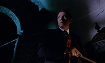 Movie still from “Blood and Black Lace” (1964), directed by Mario Bava – A man in a suit and tie holding a stick; Medium shot, Low angle