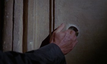 Movie still from “Blood and Black Lace” (1964), directed by Mario Bava – A man is opening a hole in the wall; Extreme Close Up shot, High angle