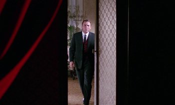 Movie still from “Blood and Black Lace” (1964), directed by Mario Bava – A man in a suit and tie walking through a doorway; Medium shot, Low angle