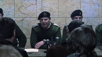 Movie still from “Bloody Sunday” (2002), directed by Paul Greengrass – A group of men sitting at a table with microphones; Medium shot, Over the shoulder angle