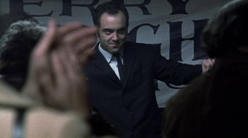 Movie still from “Bloody Sunday” (2002), directed by Paul Greengrass – A man wearing a suit and tie standing in front of a crowd of onlookers; Close Up shot, Low angle