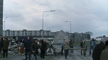 Movie still from “Bloody Sunday” (2002), directed by Paul Greengrass – A group of people standing on top of a concrete hill; Wide shot, High angle