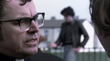 Movie still from “Bloody Sunday” (2002), directed by Paul Greengrass – An older man wearing glasses and a black jacket; Close Up shot, Low angle