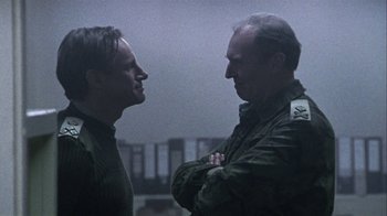 Movie still from “Bloody Sunday” (2002), directed by Paul Greengrass – Two men standing next to each other on a foggy day; Medium shot, Over the shoulder angle