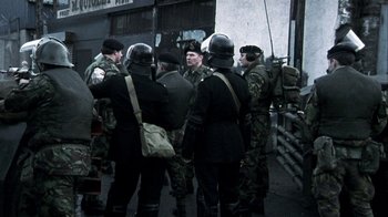 Movie still from “Bloody Sunday” (2002), directed by Paul Greengrass – A group of men standing next to each other on a street; Wide shot, Over the shoulder angle