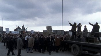 Movie still from “Bloody Sunday” (2002), directed by Paul Greengrass – A large group of people protesting on the side of the road; Wide shot, High angle
