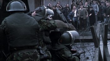 Movie still from “Bloody Sunday” (2002), directed by Paul Greengrass – A group of people standing next to each other on a street; Wide shot, High angle
