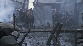 Movie still from “Bloody Sunday” (2002), directed by Paul Greengrass – A group of people standing next to barbed wire; Wide shot, High angle