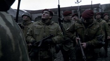 Movie still from “Bloody Sunday” (2002), directed by Paul Greengrass – A group of men standing next to each other holding guns; Medium shot, Low angle