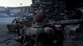 Movie still from “Bloody Sunday” (2002), directed by Paul Greengrass – A group of men in military fatigues are holding guns; Wide shot, Over the shoulder angle