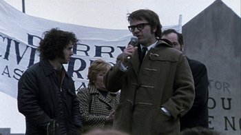 Movie still from “Bloody Sunday” (2002), directed by Paul Greengrass – A man is speaking at a rally in the 1 9 7 0 s; Medium shot, Low angle